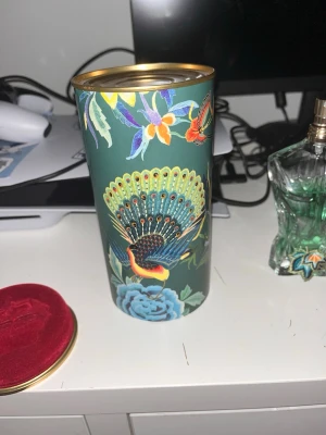 Jean Paul Gaultier Le Beau Paradise Garden - Säljer en parfym från Jean Paul Gaultier, Le Beau Paradise Garden. Flaskan är formad som en manlig torso i grönt glas med detaljer i guld och färg. Kommer i en dekorativ grön metalltub med färgglada blommor och påfågelmotiv.