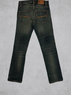  Nudie Grim Tim - Feta Nudie jeans med snygg fade och ett orange  märke på fickorna. Storlek 28/32 Midja:34cm Längd:96cm Innerbenslängd:75cm