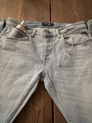 Ljusblå straight leg Replay jeans - Säljer ett par ljusblå jeans från Replay med klassisk femficksdesign och raka ben. Jeansen har en snygg tvättad look och är tillverkade i mjukt denimtyg. Perfekta för en avslappnad och trendig stil. Jeansen är endast använda 2-3 gånger och är i storlek W 33 och L 34.