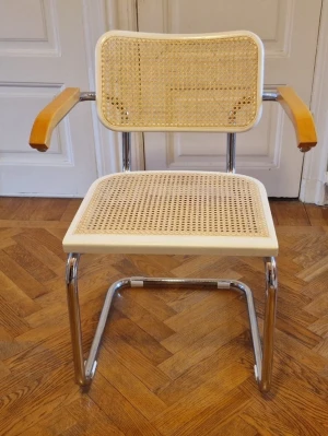 Klassisk stol med rotting och krom - Säljer en stilren stol med sits och ryggstöd i ljus rotting, ram i kromat stål och armstöd i ljust trä. Stolen har en modern design med böjda former och passar perfekt som skrivbordsstol eller i vardagsrummet.