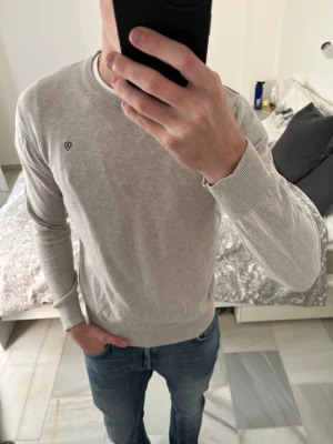 Beige stickad tröja från Alvaro Moreno - Säljer en stilren beige stickad tröja från Alvaro Moreno med rund halsringning och diskret logga på bröstet. Materialet känns mjukt och lätt, perfekt för lager på lager.