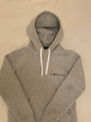Polo Ralph Lauren hoodie - Snygg ljusgrå hoodie från Ralph Lauren. Hoodien är i nyskick. Storlek M. Modellen på bilden är 184cm.