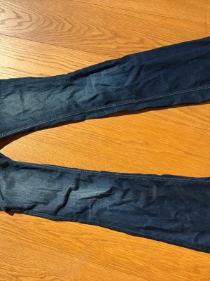 Mörkblå bootcut jeans - Snygga mörkblå bootcut jeans med klassisk femficksdesign och smala ben. Jeansen har en lätt tvättad look och är tillverkade i stretchigt denim för en bekväm passform. Vintage jenas från Gina säljs inte längs och långa i passformen 