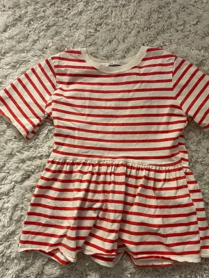 Randig peplumtop från Zara - Superfin peplumtop från Zara i vitt och rött med horisontella ränder. Toppen har korta ärmar, rund halsringning och en volangig peplum nedtill som ger en söt och avslappnad look. Perfekt att styla med jeans eller kjol för en trendig vibe. Skriv om ni har frågor eller vill köpa🙏💕