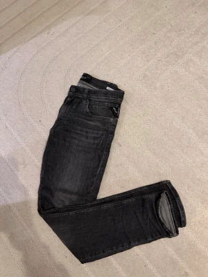 Mörkgrå slim fit jeans från replay - Snygga mörkgrå slim fit jeans från replay med klassisk femficksdesign och diskret logotyp på fickan. Jeansen har en smal passform och är tillverkade i stretchigt denimtyg för extra komfort. Perfekta för en trendig och avslappnad look.
