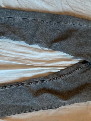 Grå raka jeans i denim - Säljer ett par grå jeans i klassisk rak modell. Jeansen är tillverkade i denim och har en enkel, stilren look utan synliga slitningar eller dekorationer. Perfekta för dig som gillar en clean och tidlös stil. Kan diskutera pris