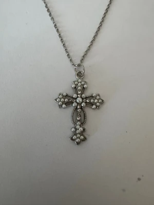 Halsband silvrigt kors med silverstenar och vita pärlor - Halsband som inte är i äkta silver/guld. Kedja är oftast 50cm men kan ibland komma i 45cm. Kedja är rostfritt stål, berlock oftast i zinklegering men kan även det i vissa fall vara rostfritt stål. Be gärna om mått på berlock om detta är viktigt då bilderna är missvisande när det gäller hur stora dom är! 🌹❤️  Allt är nytt.  Bud accepteras inte 🥰🌹