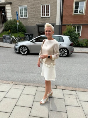 Äkta Michael Kors beige handväska - Snygg beige handväska från Michael Kors med MK-logga i mönstret och guldfärgade detaljer. Väskan har bruna axelremmar och en rund MK-berlock. Perfekt för dig som gillar stilrena accessoarer med lyxig känsla.