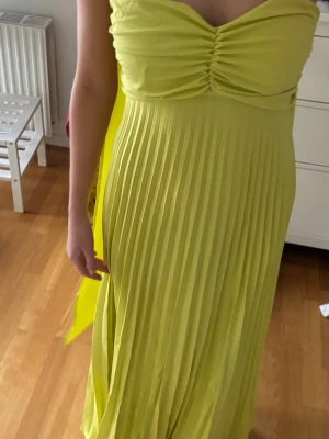 Ljusgrön plisserad långklänning - Säljer en ljusgrön långklänning med snygg snörning i ryggen. Klänningen har en medföljande scarf 