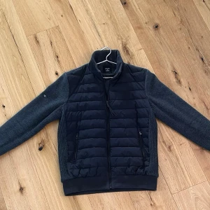 Superdry studios Cardiganjacka - Stilren jacka från Superdry Studios med quiltad front och stretchiga bommullsärmar. Bekväm, varm och perfekt för vår/höst eller svalare dagar. Väldigt fint skick.