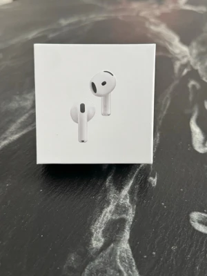 Apple AirPods 4 - Säljer ett par oanvända Apple AirPods 4 i vit färg. Trådlösa in-ear-hörlurar med stilren och kompakt design. Kommer i originalförpackning med klassisk Apple-logga. Perfekta för musik, samtal och vardagsbruk.