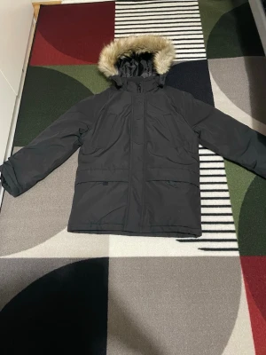 🧥 Vinterjacka i storlek 152 – oanvänd & i nyskick ❄️✨ - Stilren och varm vinterjacka i storlek 152, helt oanvänd och i perfekt skick. Jackan har en snygg svart färg som passar till allt och en huva med mjuk fuskpäls, perfekt för kalla dagar ❄️🖤  Den är välfodrad och håller värmen bra under höst och vinter. Bekväm passform med dragkedja framtill och praktiska fickor. Perfekt för skola, vardag eller utomhusaktiviteter 🏫🌨️  ✔️ Oanvänd ✔️ Storlek 152 ✔️ Varm & bekväm ✔️ Snygg och tidlös design  Redo att användas direkt – inget slitage alls! ✨