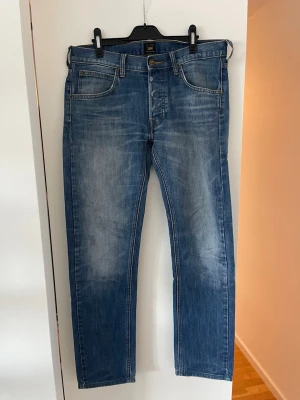 Blåa Lee Daren jeans - Säljer ett par klassiska blå jeans från Lee i modell Daren med raka ben och fem fickor i storlek W32 L34 . Jeansen är tillverkade i denim med en autentisk tvättad look. Tecken på användning på baksida. 