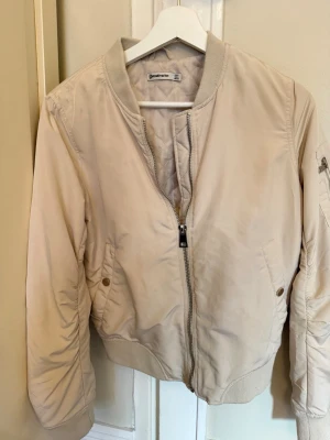 Benvit bomberjacka  - Snygg benvit bomberjacka. Jackan har några fläckar som man kan se på bild 3 och 4