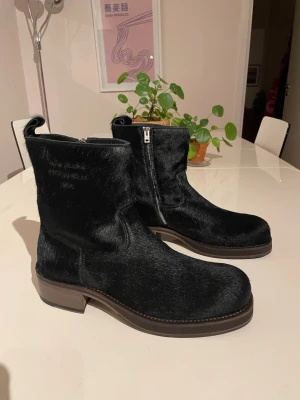 Svarta boots från Acne Studios - Säljer ett par svarta boots från Acne Studios med päls yta och dragkedja på sidan. Bootsens design är stilren med rundad tå och robust sula. 