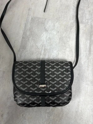 Svart/brun axelväska - Extremt skön axelväska som funkar för varje tillfälle. Knappast rörd och är i extrem bra tillstånd. Får plats med en Hel del saker och håller sig tight stängd. Däröver är den lätt att bära