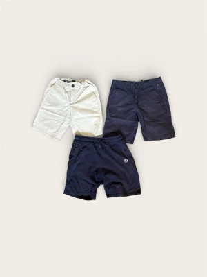 Paket: 3 st Märkesshorts (Tommy Hilfiger & Henri Lloyd) – Stl 152 / 12-13 år - Säljer ett färdigt klädpaket med tre snygga märkesshorts för barn/ungdom i mycket fint skick. Perfekt tillfälle att uppdatera vår- och sommargarderoben med kvalitetskläder i ett enda köp.  Paketet innehåller:  1 par ljusa/beige shorts: Tommy Hilfiger, storlek 152.  1 par mörkblå chinos-shorts: Tommy Hilfiger, storlek 152.  1 par mörkblå mjukisshorts (nederst på bilden): Henri Lloyd, storlek 12-13 år.  Skick: Alla tre är i mycket fint skick. Mitt hem är helt djur- och rökfritt.  Pris: 299 kr