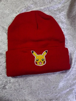 Pokémon Barn Mössa  - Säljer två stickade mössor i rött och blått med en broderad Pikachu på uppviket. Perfekt för dig som älskar Pokémon och vill ha en färgglad accessoar till vintern. Mössorna är ribbstickade och har en klassisk passform. 99kr/st 