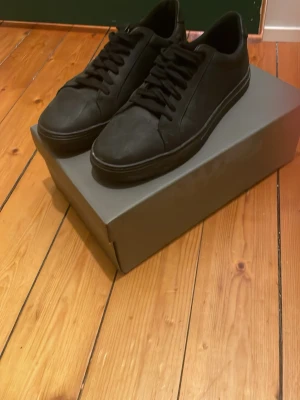 Vagabond sneakers - Snygga helsvarta sneakers med clean och stilren design. Skorna har lågt skaft, svarta skosnören och en matchande svart sula. Perfekta för dig som gillar en enkel och modern look. Materialet ser ut att vara slätt läder eller syntet.