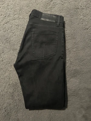 Svarta slim fit jeans - Säljer ett par svarta slim fit jeans med klassisk femficksdesign och silverfärgade nitar. Jeansen har normal midja och raka ben. Materialet är mjukt och stretchigt för extra komfort. Perfekta till en avslappnad streetwear-look.