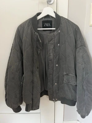Grå/ grön quiltad bomberjacka från Zara - Snygg och populär grå/grön bomberjacka från Zara med quiltat mönster. Oversized passform för en trendig look.