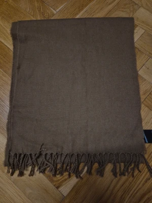 Brun halsduk med fransar - Mått: 180×35 cm Använt, mycket bra skick.