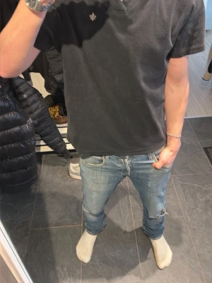 Svart pikétröja från Morris - Klassisk svart pikétröja från Morris med korta ärmar och liten broderad logga på bröstet. Tröjan har mjukt material och krage med knappslå. Perfekt till jeans eller shorts för en avslappnad stil.