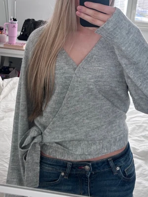 Grå omlottstickad tröjä - Grå omlottstickad tröjä i storlek XS. Använd endast några gånger, i fint skick🥰 Säljer även en likadan i rosa i storlek S.