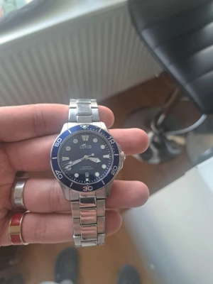 Lotus herrklocka med blå urtavla - Stilren herrklocka från Lotus med blå urtavla och silverfärgat armband i metall. Klockan har tydliga index, datumvisning och vridbar bezel. Klassisk design som passar till många stilar. Quartz-urverk och robust länkarmband.