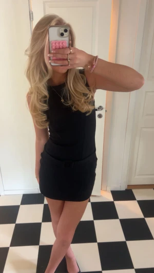 Svart ärmlös kortklänning - Säljer en stilren svart kortklänning med ärmlös design och rund halsringning. Klänningen har en figurnära passform och enkel, klassisk look som passar perfekt till många tillfällen. Materialet känns mjukt och följsamt mot kroppen.