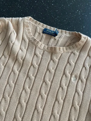 Polo Ralph Lauren Beige kabelstickad - En beige stickad Ralph Lauren tröja med liten vit häst där fram Jätte jättefin har absolut älskat denna har börjat bli för liten på mig Köpte i USA för några år sen på en familjesemester XS