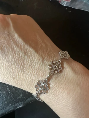 Silverfärgat armband med hjärtformade länkar - Ett snyggt armband i silverfärg med flera hjärtformade länkar som är sammanlänkade. Armbandet har ett klassiskt lås och detaljerade mönster i varje länk. Perfekt för dig som gillar stilrena och romantiska accessoarer.