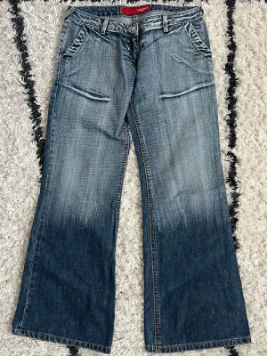 Jeans  - Säljer ett par blå lågmidjade raka jeans med snygga slitningar och tvättade detaljer. Jeansen har framfickor med sned öppning och breda benslut för en retro vibe. Storlek W31/L30 💙  