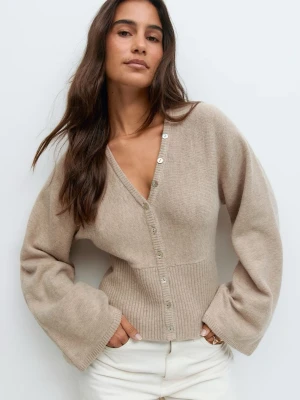 Beige tröja med vida ärmar - Trendig beige tröja med v-ringning och vida ärmar. Koftan har ribbad midja och knäpps med silvriga knappar framtill. Mjuk och skön stickad kvalitet. Använd 1 gång, nypris 400kr.