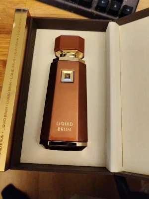 Liquid Brun edp - Exklusiv parfym från Liquid Brun i en brun och guldig flaska med geometrisk, kantig design. Flaskan har gulddetaljer och en unik form som verkligen sticker ut på hyllan. Perfekt för dig som gillar stilrena och lyxiga parfymer. Använt ca 15ml (mycket kvar) hämtas i Solna endast 