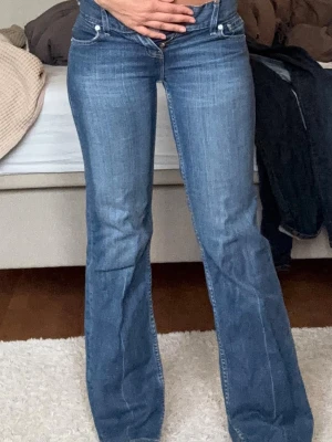 Blå bootcut jeans från Levi's - Säljer ett par klassiska blå bootcut jeans från Levi's med låg midja. Jeansen har en snygg tvättad look, Levi's ikoniska röda lapp på bakfickan och skinnpatch i midjan. Perfekta för dig som gillar vintage stil och vill ha ett par jeans med riktigt bra passform.obs! dragkedjan är trasig men är en enkel fixa! inerbenslängd:71 midjemått tvärsöver:36💕