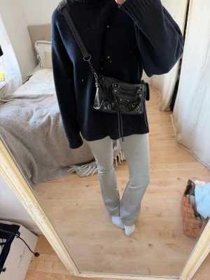 Svart city liknande handväska  - Säljer en svart handväska från liknande den klassiska city-modell. Väskan är gjord i mjukt skinn med silverfärgade detaljer, dragkedja och dekorativa nitar. Justerbar axelrem och cool, slouchy form. Perfekt för dig som gillar edgy och tidlös design. Liten defekt vid handtaget 