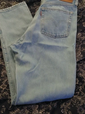 Ljusblå Levi's raka jeans 501,storlek W29 L32 - Säljer ett par klassiska ljusblå jeans från Levi's 501 med rak passform och hög midja. Jeansen har den ikoniska röda Levi's-lappen på bakfickan och är tillverkade i slitstark denim. Perfekta för en avslappnad och trendig look.Byxor är använda bara en gång, nypris var 1490 kr