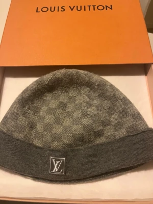 Grå LV Mössa (Äkta) - Säljer min äkta gråa lv mössa med 1 litet hål där och de va ett litet hål därframme som jag har fixat dene bra skit snygg passform har fixat och krymt den till den perfekta formen.