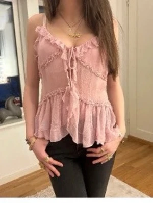 Zara XS viral rosa volang topp linne Y2K feminin - Viral Zara rosa y2k topp med volanger och snörning framtill. Storlek XS. Tunt, luftigt material och smala axelband. Perfekt för varma dagar och ger en romantisk vibe till outfiten. Passar snyggt till både jeans och kjol. Jättefint skick! Obs! Lånade bilder på, för liten för mig nu :(
