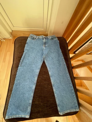 Blå raka jeans från Lee - Klassiska blå jeans från Lee med rak passform och hög midja. Jeansen har fem fickor, bälteshällor och Lee-lapp bak i midjan. Tillverkade i slitstark denim som ger en tidlös look. Perfekta till sneakers eller boots. Aldrig används för jag köpte fel storlek