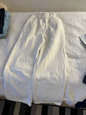Vita vida mjukisbyxor med resår - Säljer ett par vita mjukisbyxor med bred passform och resår i midjan. Byxorna har en avslappnad look och är perfekta för chill dagar. Tillverkade i mjukt material som känns skönt mot huden. Inga synliga loggor eller detaljer.