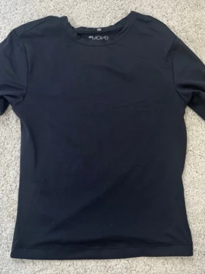 Svart träningströja från H&M Move - En enkel och stilren svart träningströja från H&M Move. Tröjan har rund halsringning och är tillverkad i ett mjukt, stretchigt material som passar perfekt för träning eller sportaktiviteter.