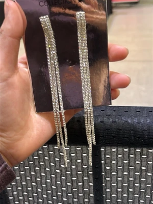 Långa glittriga örhängen Ur & Penn - Säljer ett par långa, silvriga örhängen från Ur & Penn. Örhängena har flera rader med gnistrande stenar som ger en riktigt lyxig känsla. Perfekta för dig som vill sticka ut och addera extra bling till din look. Stift med plastbaksida. Den är aldrig använd. 