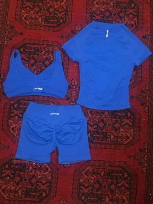 Blått träningsset från DFYNE - Snyggt blått träningsset från DFYNE med sport-bh, tight t-shirt och shorts. Setet är gjort i stretchigt funktionsmaterial som andas och passar perfekt till gymmet eller löpning. Logga på alla delar och shorts med scrunch-detalj bak.