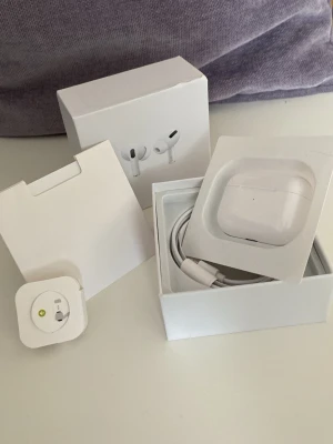 Apple AirPods Pro med laddningsetui - Säljer ett par vita Apple AirPods Pro med trådlöst laddningsetui. Kommer i originalförpackning med USB-C laddkabel och adapter. Snygg och stilren design i blank plast, perfekt för dig som vill ha grymt ljud och smidig anslutning till din iPhone.
