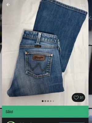Blå bootcut jeans från Wrangler - Snygga blå bootcut jeans från Wrangler med klassisk femficksdesign och logga på bakfickan. Jeansen har låg/mid midja, 