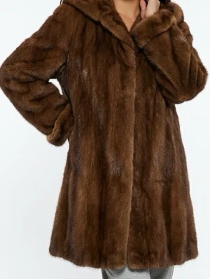 Brun saga mink päls kappa med krage - Snygg brun saga mink päls kappa med bred krage och långa ärmar. Kappan har en rak passform och känns riktigt lyxig och varm. Perfekt för dig som vill ha en trendig och mysig look under kalla dagar.