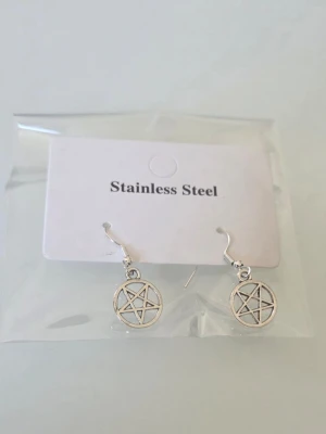 Silvriga pentagram örhängen i stål - Snygga örhängen i rostfritt stål med pentagramdesign. De är silvriga och har en rund form med en stjärna i mitten. Perfekta för dig som gillar alternativ stil och vill ha något unikt till din look.