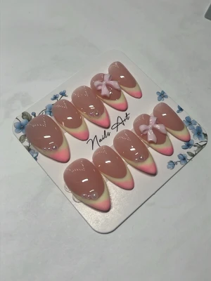 Press-on naglar rosa ombre med rosetter - Snygga press-on naglar i almondform med rosa och ljus gul ombre -french, dekorerade med små pärlor och två 3D-rosetter. Naglarna har en glansig finish och kommer i en söt förpackning. Perfekt för dig som vill ha en gullig och trendig look. Det följer med prepp kitt och limm vid köp av naglar 🌸